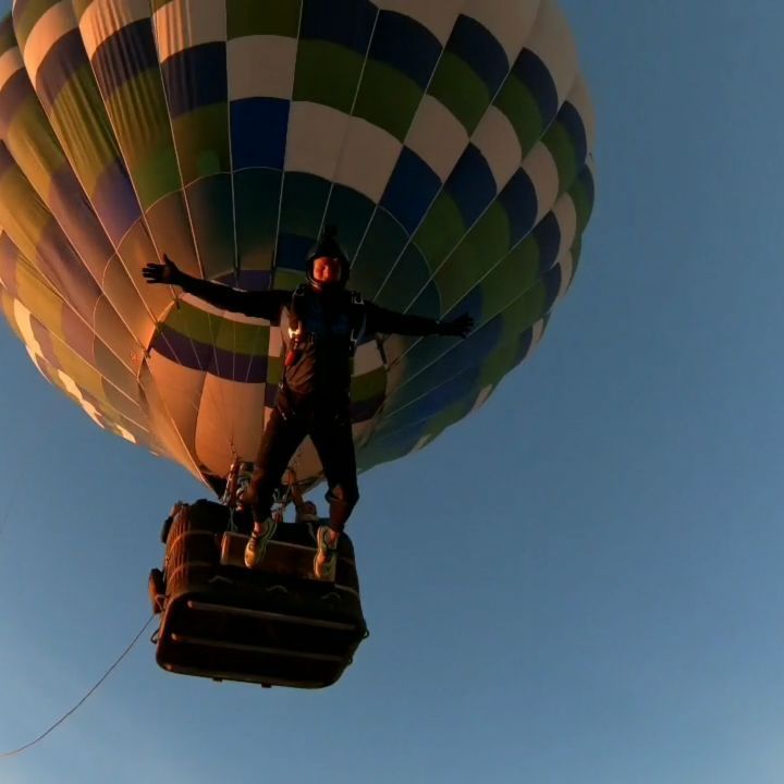Danny standing on top of a hot air balloon basket in flight