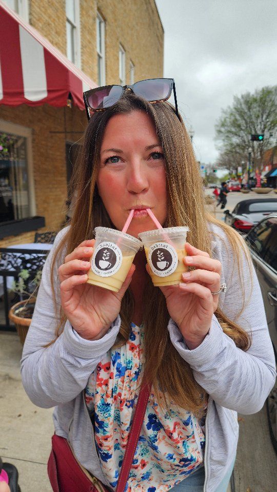 Laura with a drink in each hand in downtown McKinney