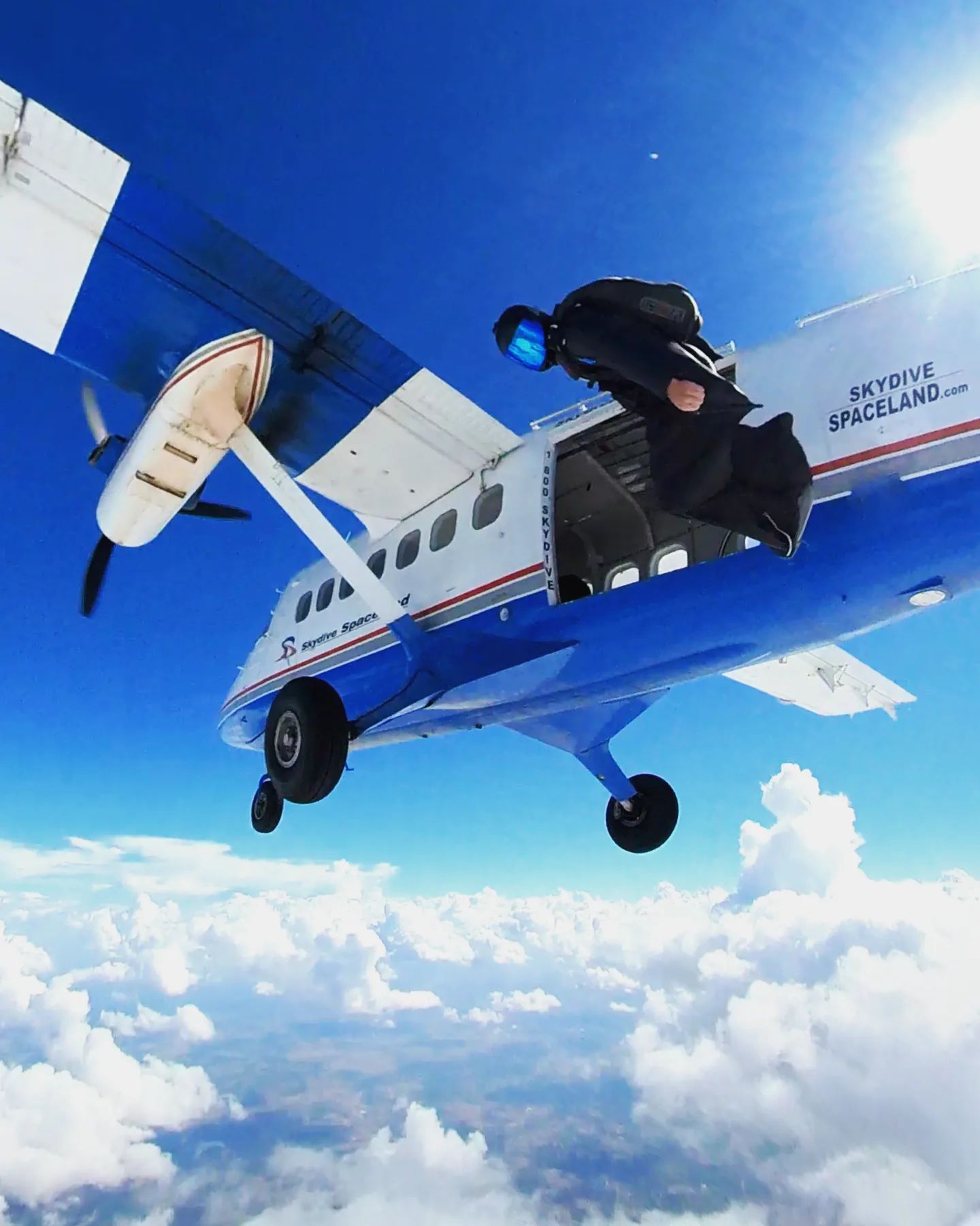Wingsuit pilots exiting an airplane above the clouds